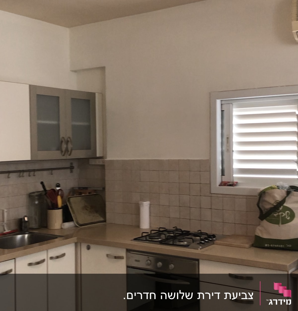 מטבח עם קיר צבוע בלבן, כלים על השיש